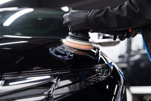 Dual-action polisher buffing a glossy black hood while applying ceramic coating in Chula Vista