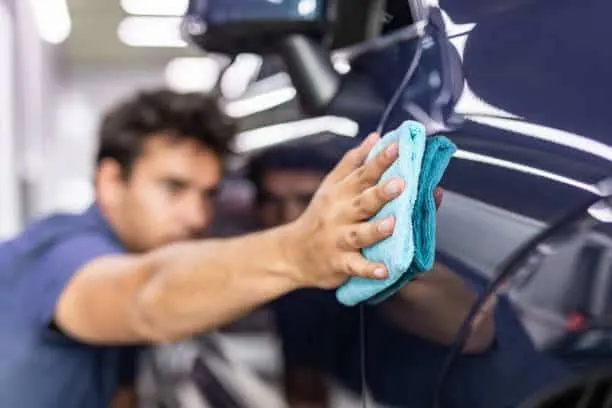 Detailer wiping down vehicle paint with a microfiber towel during a maintenance detail in Chula Vista